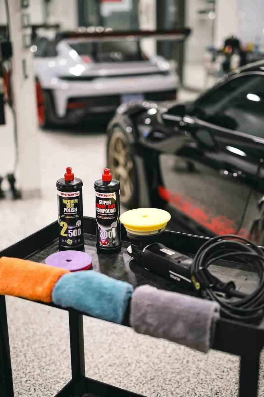 Premium paint correction products and tools for vehicle detailing on display in a garage.